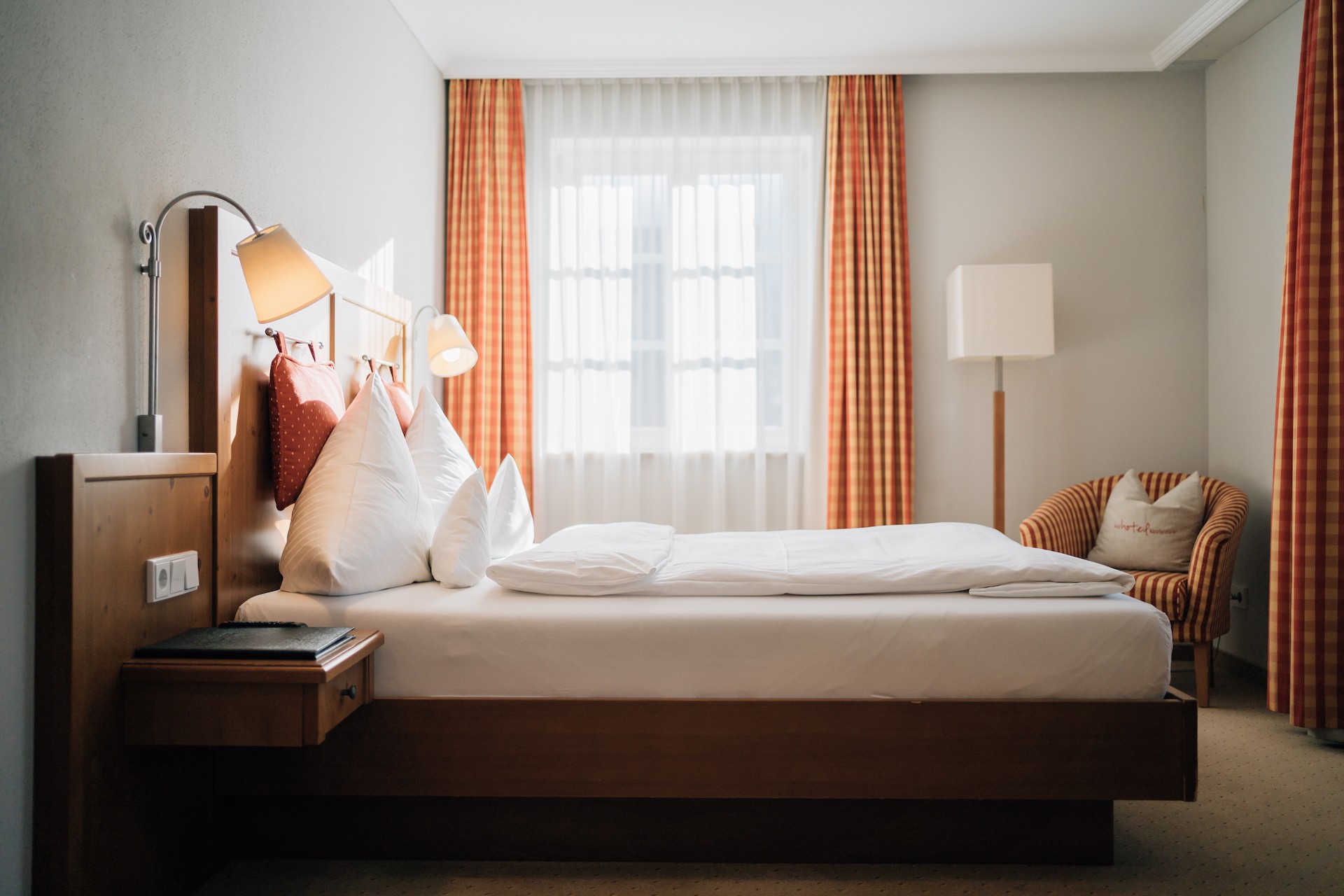 Ein Standard Hotelzimmer im Klostermeier Hotel Icking bei Wolfratshausen - Doppelbett mit Stuhl, Lampe, Nachttisch und geöffnetem Fenster