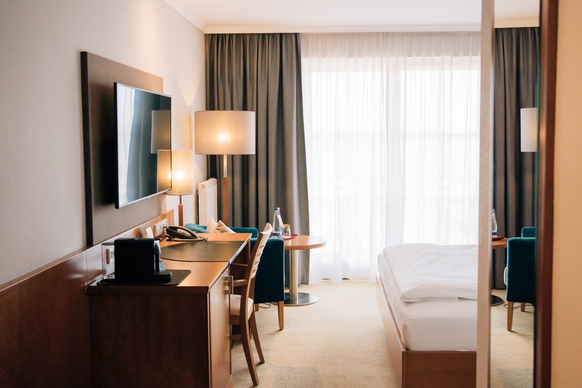 Ein Superior Zimmer im Klostermeier Hotel Icking in der Nähe von Wolfratshausen München. Mit Bett Fernseher, Stehlampen und Balkon